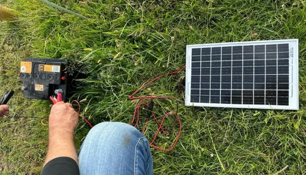 Mini solar panel with alligator clips connected to a 12V battery for solar charging