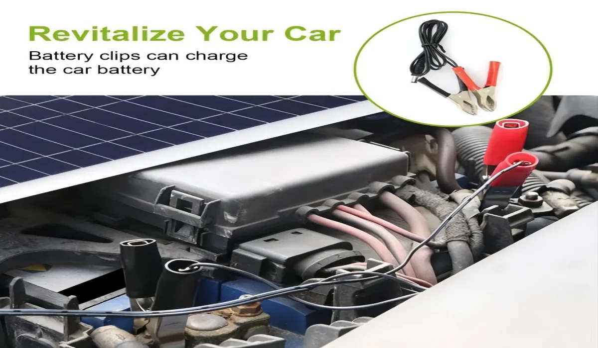 Portable solar panel with alligator clips charging a car battery outdoors